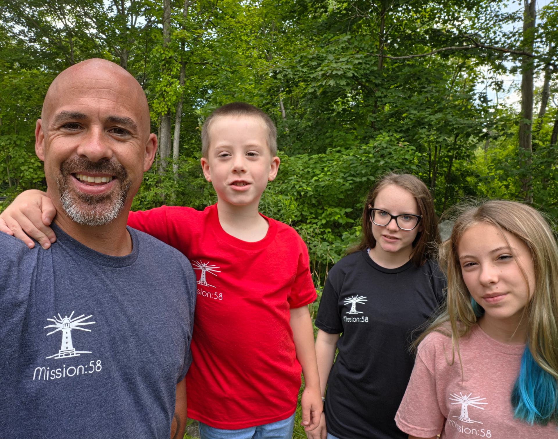 A father and three children wearing Mission:58 shirts outdoors
