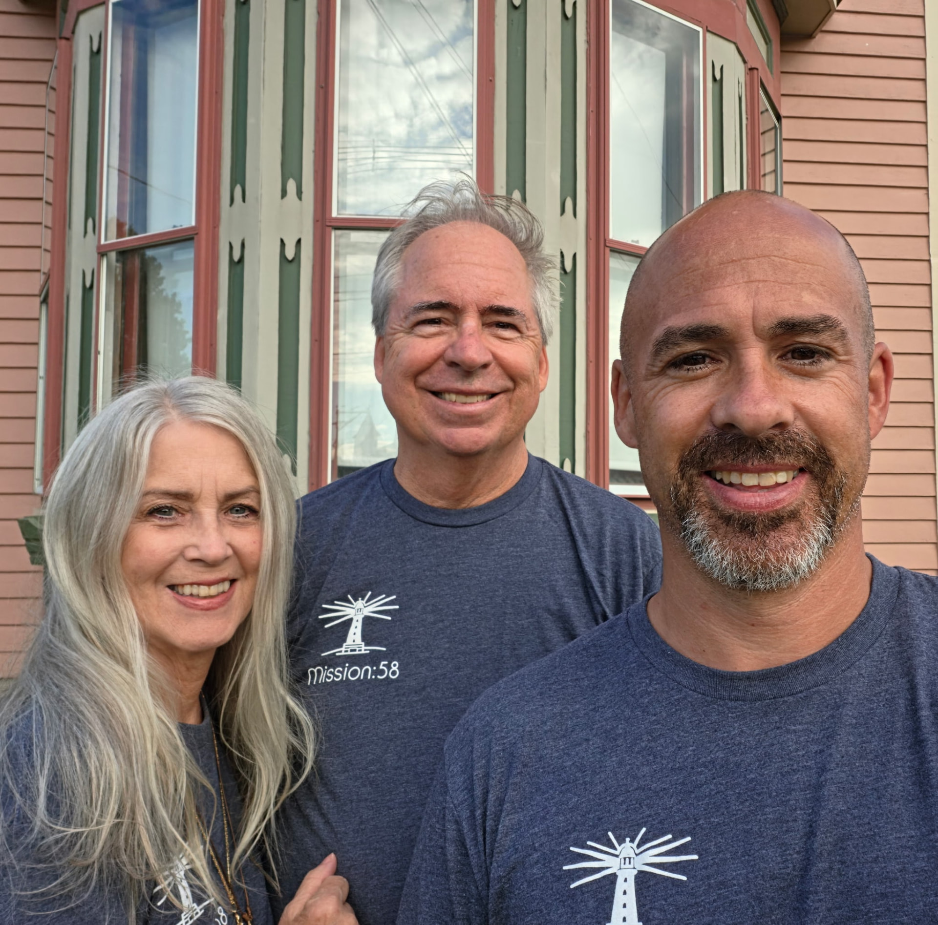 Three Lighthouse Ministries members smiling together outside a home